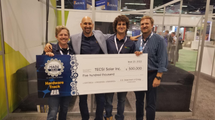 Four people stand holding a large check for five hundred thousand dollars