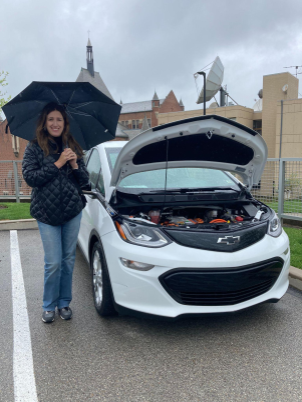 Paulina Jaramillo holds and umbrella next to her Chevy Bolt.